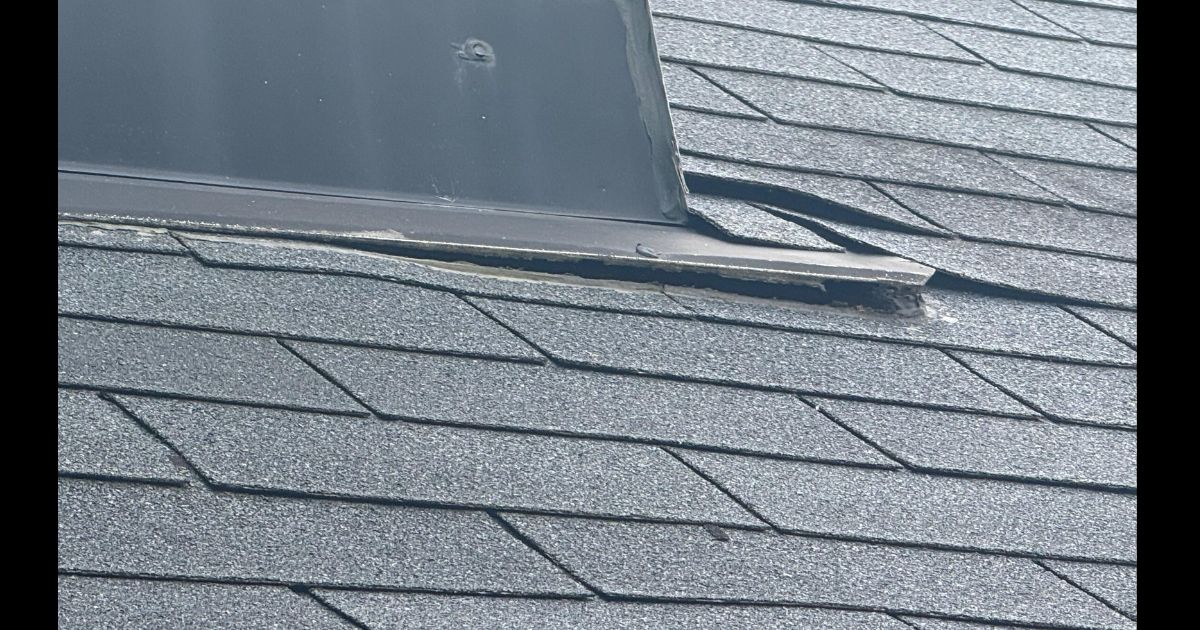 Chimney flashing showing wear and lifted edges where the metal meets the shingles — a common entry point for water intrusion after storm damage