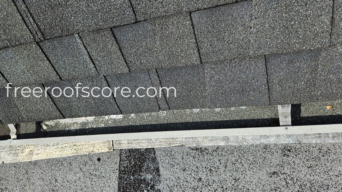 Granule loss visible in residential gutter — sand-like sediment from hail-damaged asphalt shingles